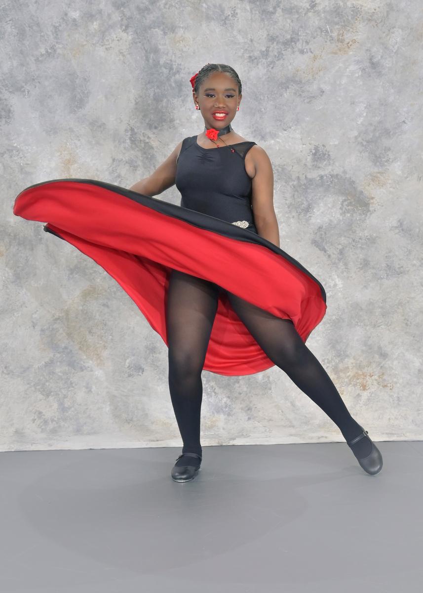 Tap dancer in a black and red dress with tap shoes striking a pose